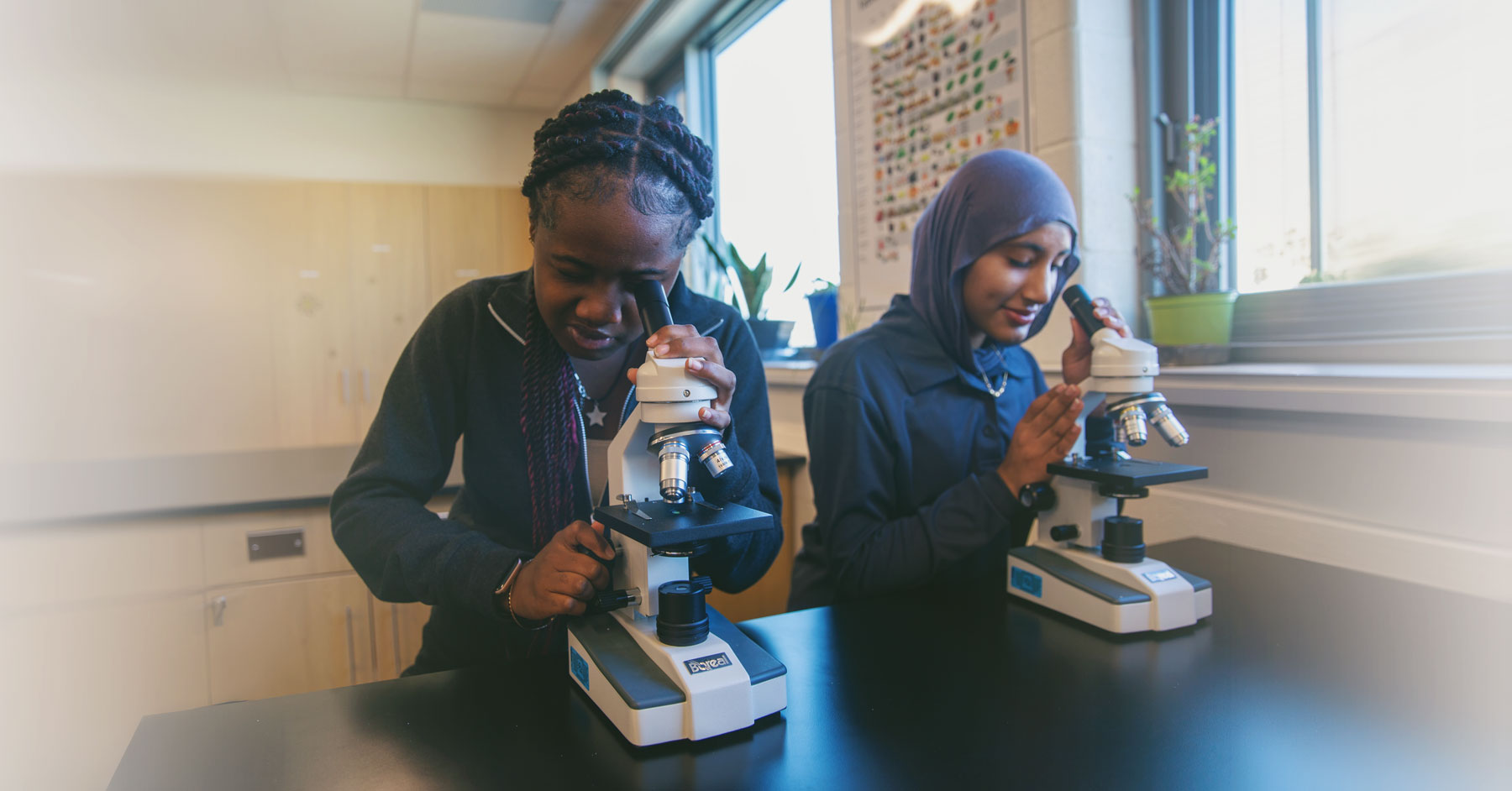 Two female St. Kateri Secondary School Students using microscopes in Science class