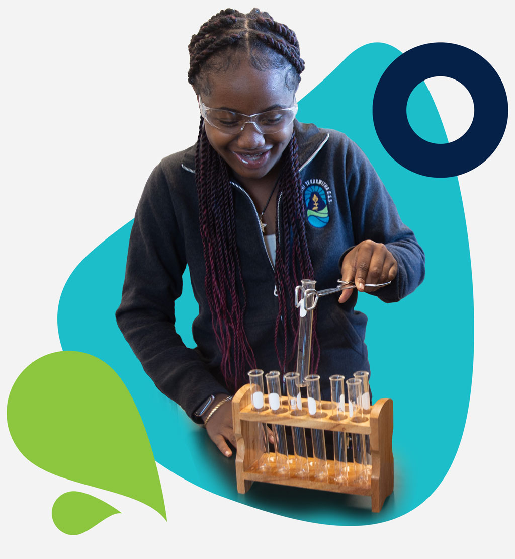 St. Kateri IB female student focused on using lifting a test tube with a clamp in Science class